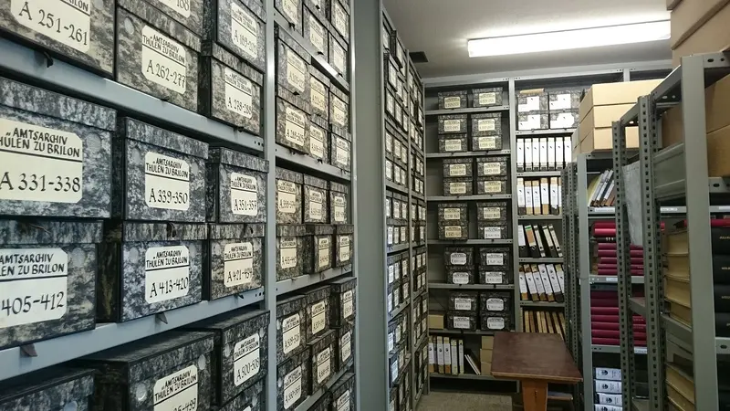 Das Magazin eines Stadtarchivs mit beschrifteten Archivkartons und Ordnern in Regalen.