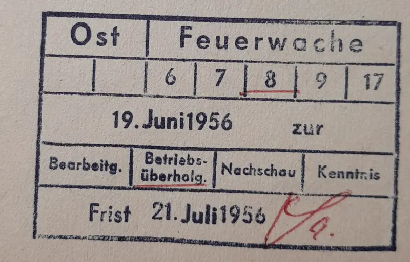 Ein alter Eingangsstempel auf Papier mit Feldern für Bearbeitung, Nachschau und Frist, daneben ein Namenszeichen in Rot.