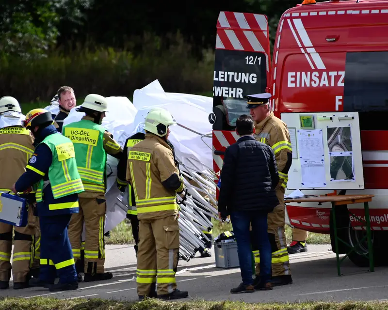 Einsatzkräfte stehen bei einer Großübung vor dem Einsatzleitwagen der Feuerwehr an einer Lagetafel.
