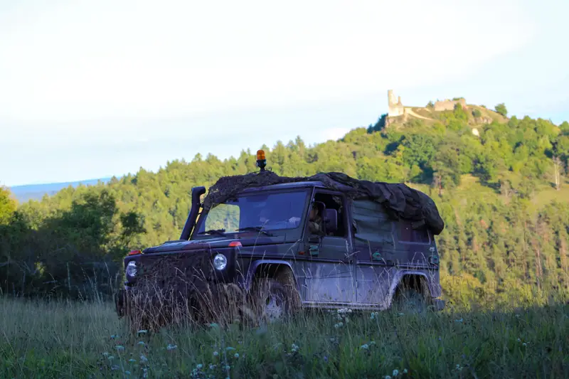 Ein getarnter Geländewagen fährt über eine Wiese im Hügelland, um einen neuen Gefechtsstand einzurichten.