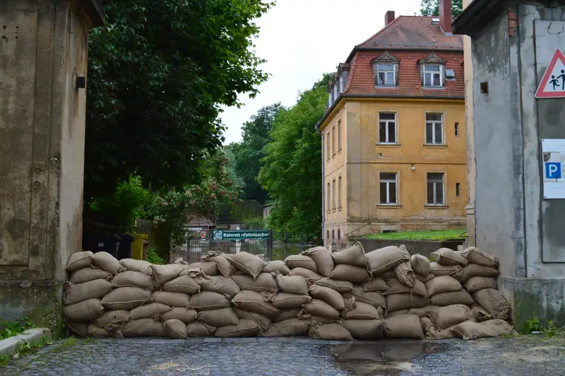 Ein Wall aus Sandsäcken sperrt eine Gasse zwischen Altbauten gegen das Hochwasser.