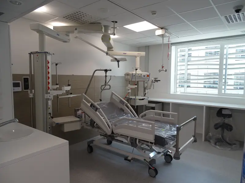 Ein leeres, frisch hergerichtetes Intensivzimmer mit Bett und Deckenversorgung.