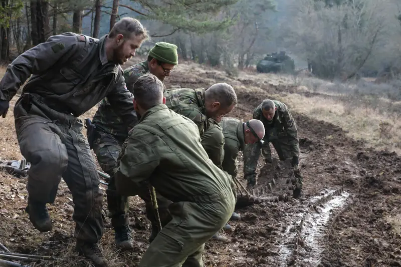 Niederländische Soldaten reparieren im Schlamm die gerissene Kette eines Schützenpanzers.