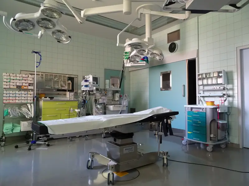 Ein leerer Operationssaal mit OP-Tisch, OP-Leuchten und Materialschränken.